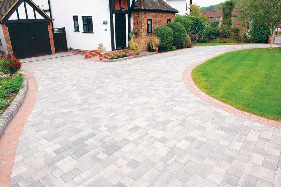 Large driveway surfaced with Brett Beta light grey block paving and contrasting red edging bricks and kerbs