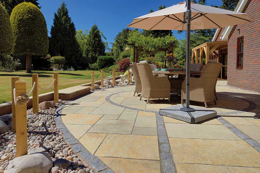 Large new limestone paved patio with contrasting edging stones and decorative pebbles