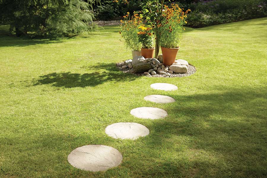 A small garden path over a lawn made with Bradstone sandstone round stepping stones