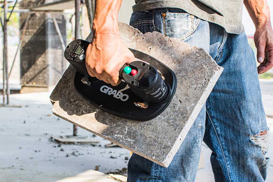 Landscaper carrying a paving slab with a Grabo electric suction lifter system