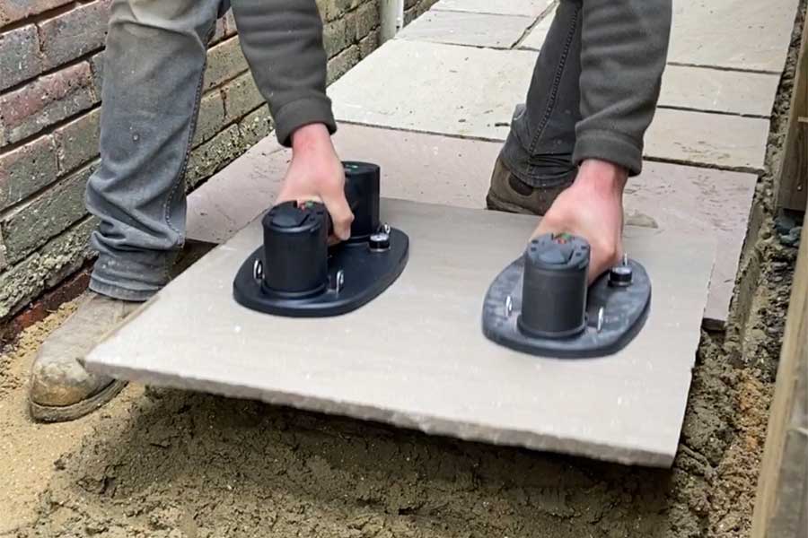 Landscaper laying a large natural stone paving slab with Grabo electric suction lifters