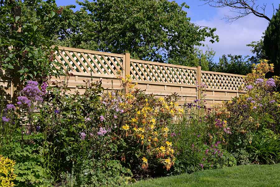 Garden fence topped with decorative lattice trellis panels