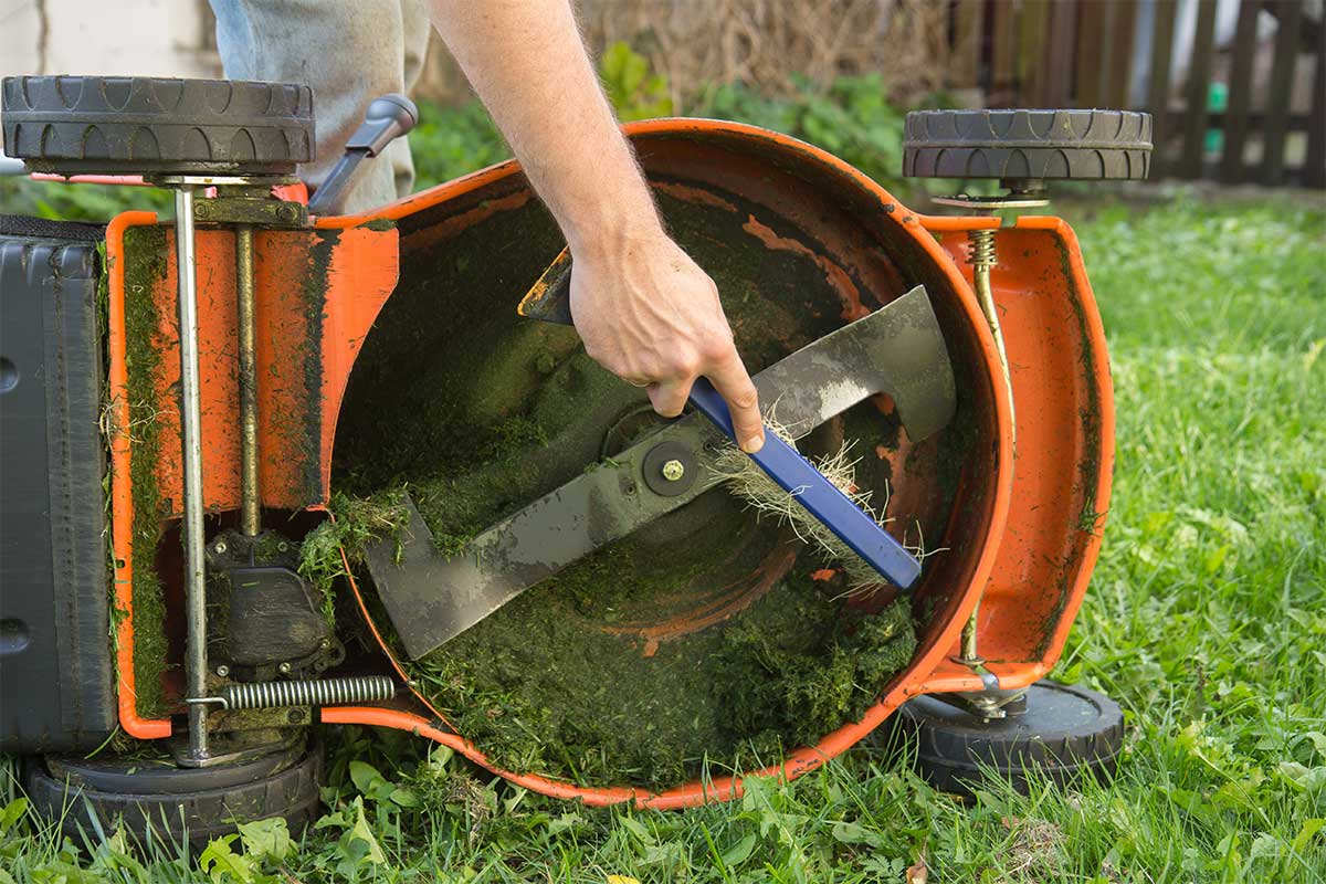 Man cleaning a lawn mower ready to store it over winter