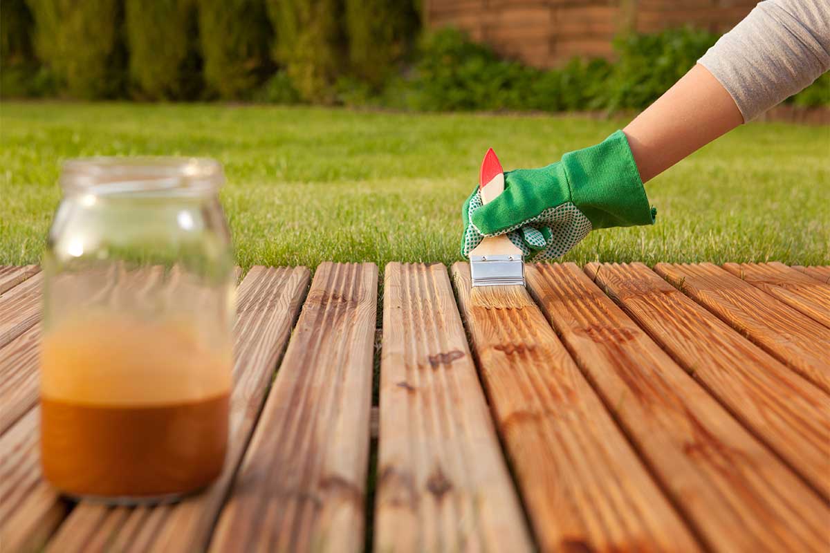 Applying protective stain to timber decking to protect it from wet winter weather and frosts