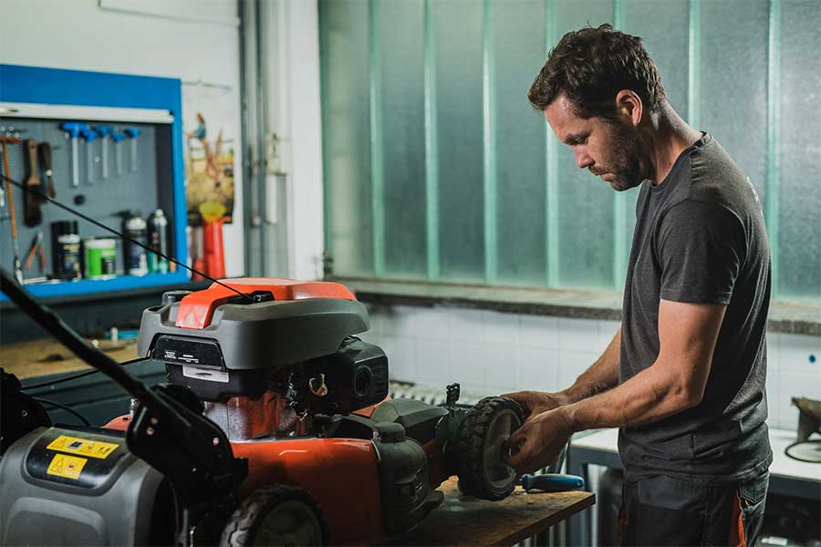 A garden machinery specialist servicing a petrol lawn mower in his workshop