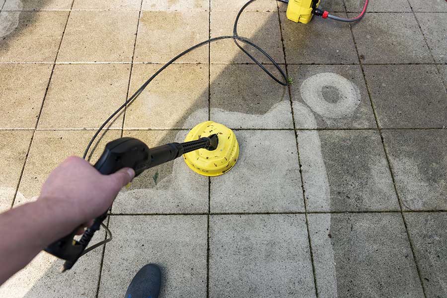 Cleaning a patio with a pressure washer attachment to remove general dirt and grim